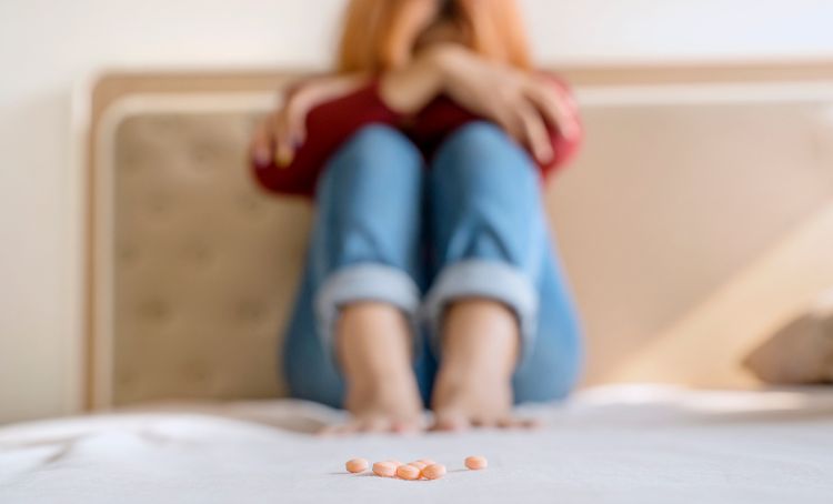 A woman sat on a bed experiencing pregabalin withdrawal symptoms - Is Pregabalin Addictive? - Step by Step Recovery
